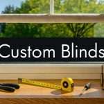Window with a beige roller blind; on the sill are tools (tape measure, pliers, screwdriver) and a jar of fasteners, conveying custom blinds installation_df.