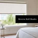 reverse-roll-roller-shades-bedroom-interior | Drapery Company Bedroom with a large window and light beige reverse roll shades; neutral bedding and a cozy seating area visible outside greenery and palm trees.