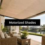 Patio seating area under a large retractable shade with wicker furniture and greenery, labeled 'Motorized Shades' in a black banner in the center