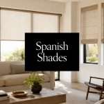 window-shades-in-spanish-living-room | Drapery Company Living room scene with a beige sofa, neutral decor, and large windows wearing beige shades; a black sign in the center reads 'Spanish Shades'