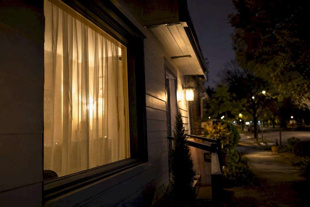 Porch light glowing near window with sheer curtains