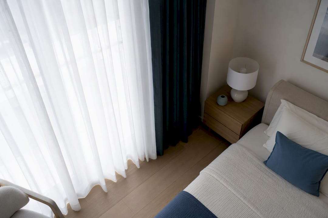 Layered sheer and blackout curtains on bedroom window