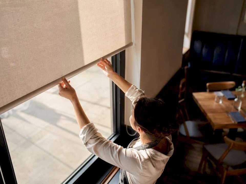 Hands adjusting roller shade in restaurant