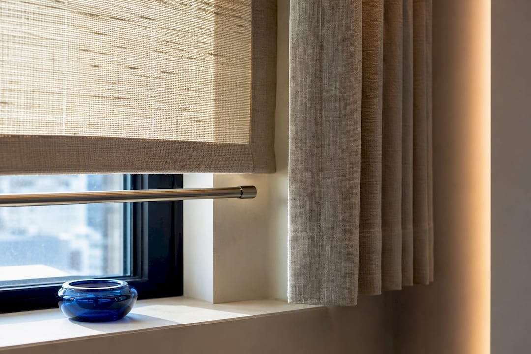 Layered shade and drapery at a window bay