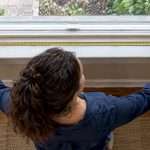 Homeowner measuring a window opening with tape